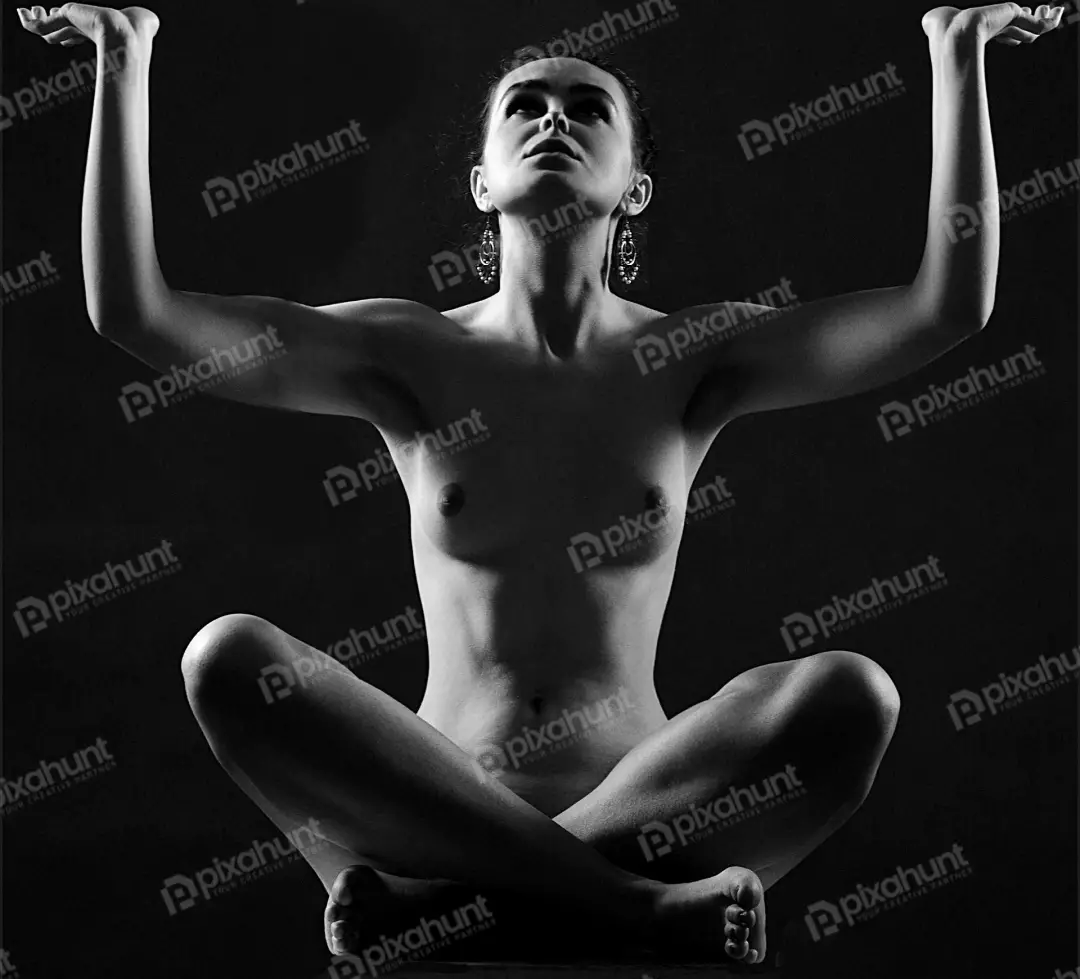 Nude woman in meditative lotus pose with raised arms black and white