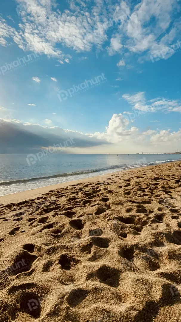 Free Premium Stock Photos Sandy Beach Footprints with Ocean Waves and Cloudy Sky