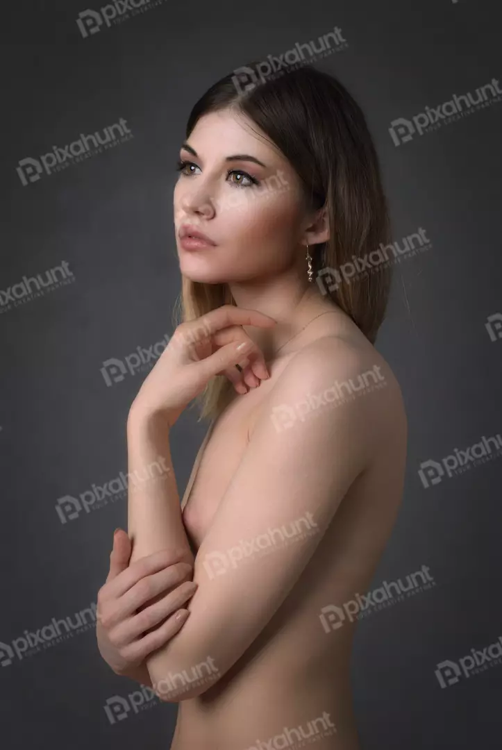 Pensive Bare-Shouldered Woman with Golden Jewelry against Dark Backdrop