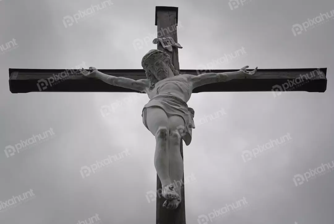 Solemn White Christ Statue on Rustic Wooden Cross Against Overcast Sky