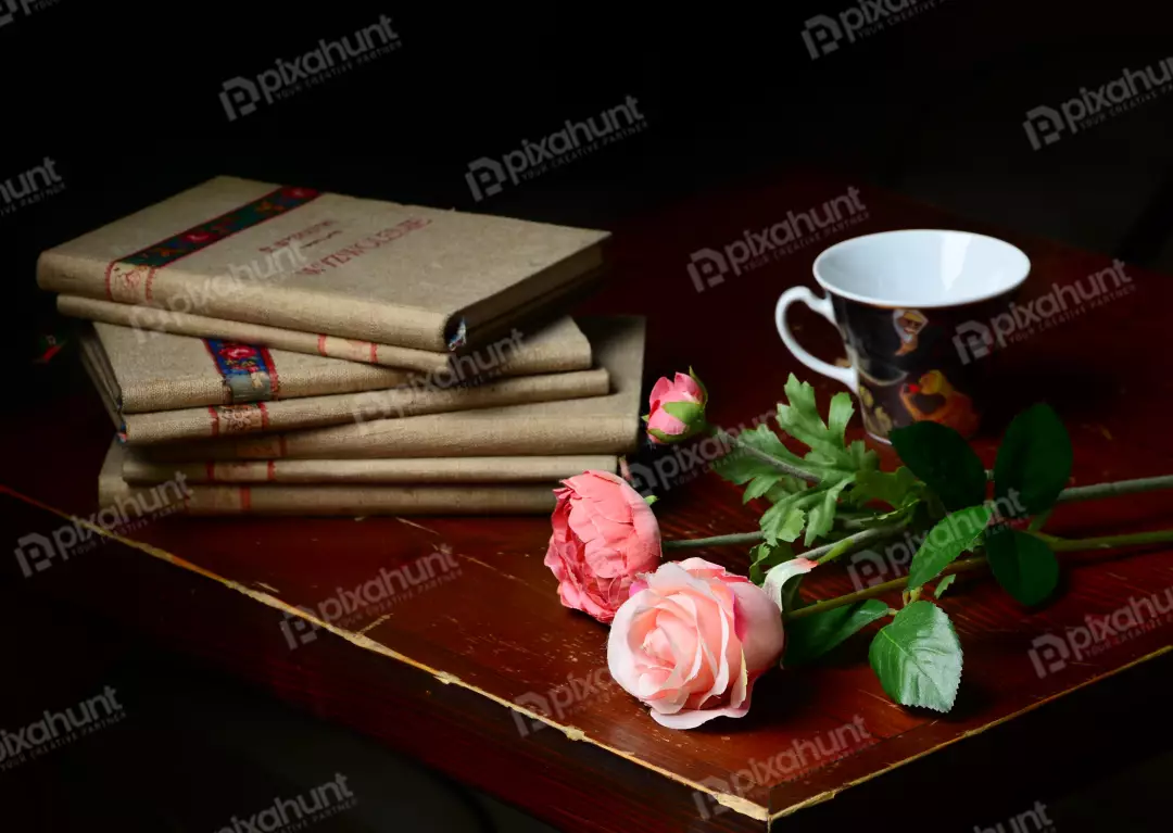 Elegant Still Life with Vintage Linen Books, Pink Roses, Tea Cup on Dark Wood Table