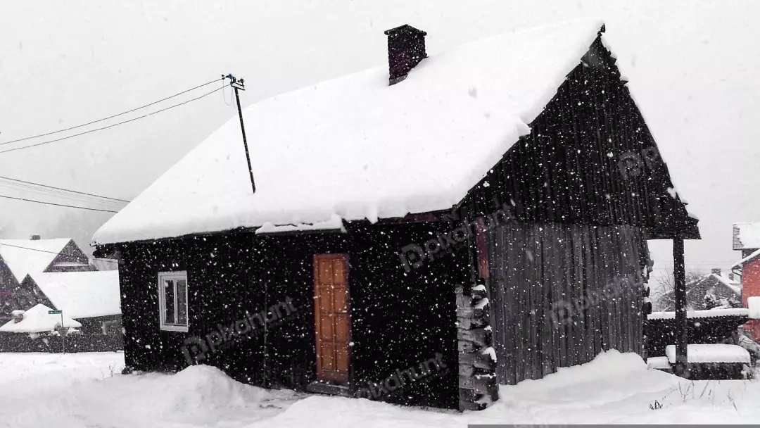 Rustic Wooden House Blanketed in Falling Snow During a Peaceful Winter Day