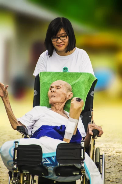 A young woman pushing an elderly man in a wheelchair