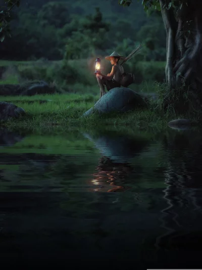 Boy sitting on a rock in the middle of a river and wearing a traditional Vietnamese hat with holding a lantern in his right hand