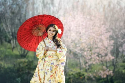 Beautiful woman wearing a traditional Japanese kimono and long dark hair is left out and girl is holding a red umbrella