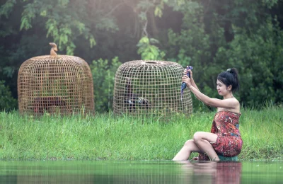 Woman look larger than life and sitting on a rock in the middle of a river with her feet in the water
