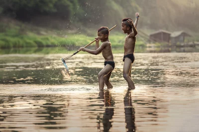 Two children boys playing in a river and boys are both smiling and appear to be having a great time