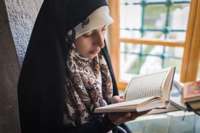Reading a book near a window. Unfortunately the person face is not visible due to blurring