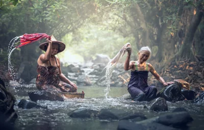 Two old women washing clothes in a river