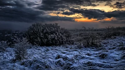 Frosted Winter Terrain Under a Dramatic Sunset Horizon image