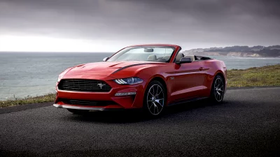 Vibrant Red Ford Mustang Convertible Parked by Scenic Ocean Coastline Under Overcast Sky image