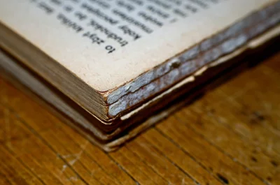 Aged Open Book with Frayed Pages on Rustic Wooden Table image