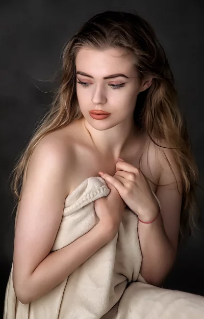 Pensive Young Woman Draped in Soft Blanket with Downcast Gaze image