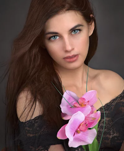 Captivating Woman with Striking Blue Eyes and Delicate Pink Orchids image