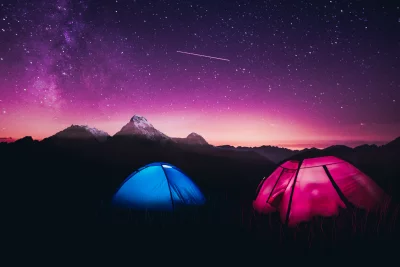 Vibrant Starry Night Camping with Illuminated Tents and Majestic Mountains image