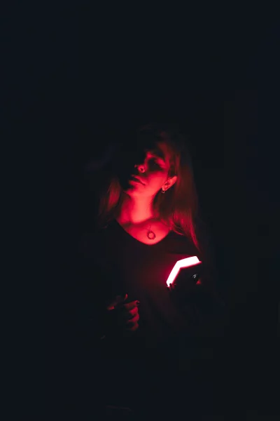 Mesmerizing female portrait illuminated by vibrant red glow and deep shadows