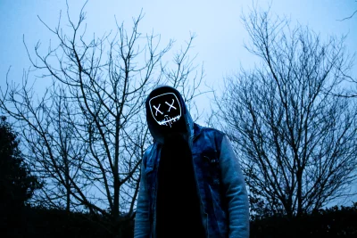 Eerie Figure with Glowing X-Face Mask Amidst Bare Winter Trees image
