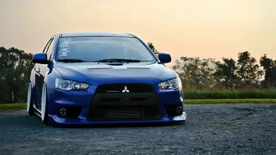 Sleek Blue Mitsubishi Lancer Evolution X Stanced on a Rural Road at Golden Sunset image