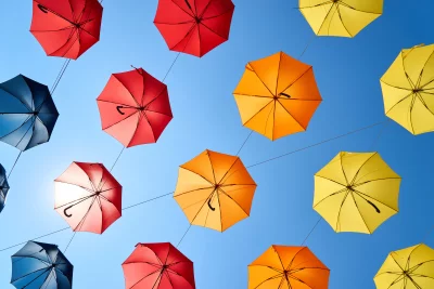 Vibrant Street Art: Colorful Umbrellas Floating Against a Clear Blue Sky Cinematic Wallpaper image