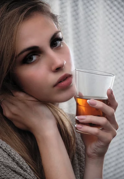 Pensive Woman Holding Amber Drink with Intense Gaze image