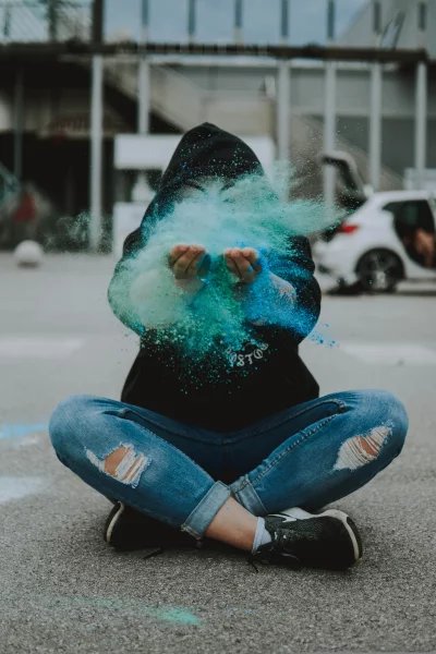 a person sitting on the ground with a colorful powder in their hands