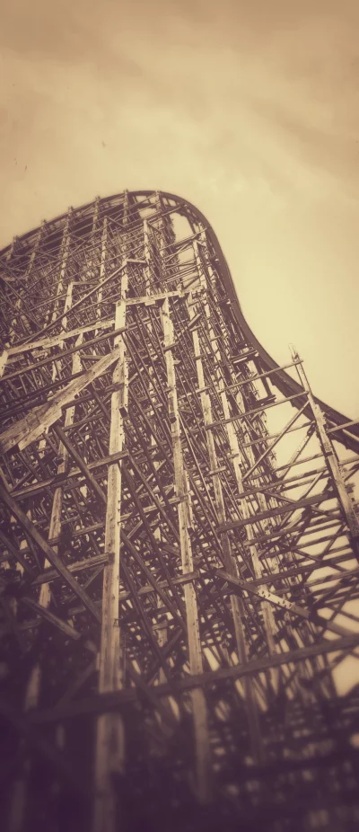 Vintage Wooden Roller Coaster Structure Reaching Towards a Moody Sepia Sky image