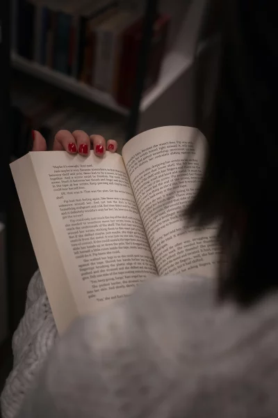 Woman's hand with red nails reading an open book