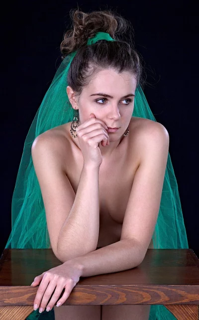 Young woman with green veil posing thoughtfully on dark background image