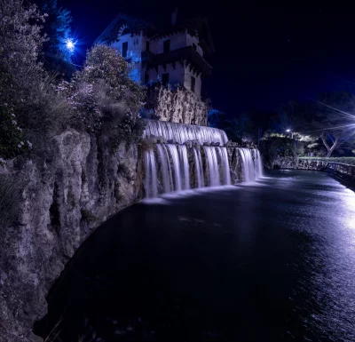 Enchanting Night Scene: Cascading Waterfall with Historic Villa Illuminated by Blue Lights image