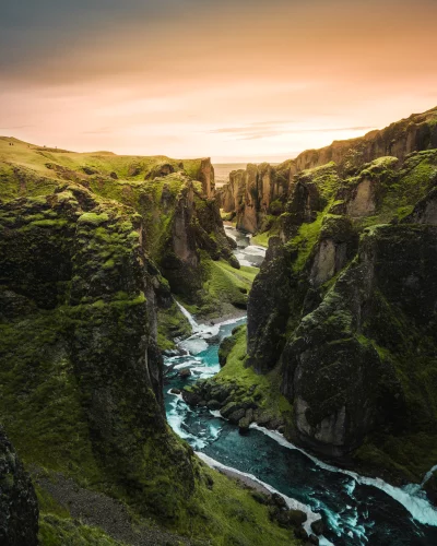Dramatic Icelandic Canyon Landscape with Vibrant Green Moss and Winding River Under Golden Sky image