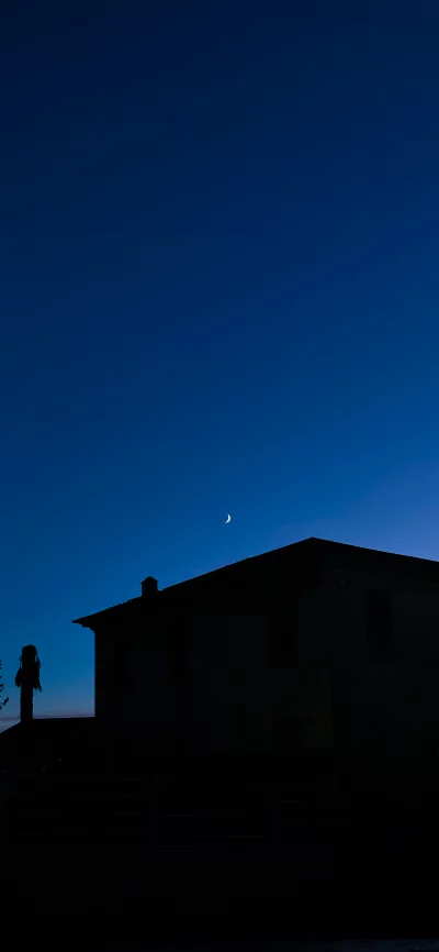 Crescent Moon Illuminates House Silhouette Against Dark Blue Night Sky image