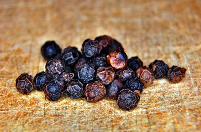 Close Up View of Aromatic Black Peppercorns on Rustic Wooden Surface image