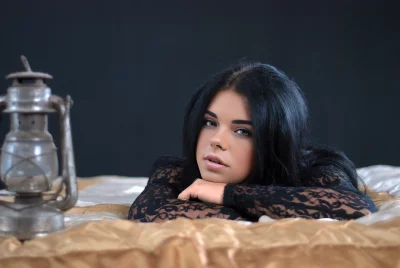Beautiful Young Woman Lying on Bed with Lace Top and Lantern Looking Thoughtfully image