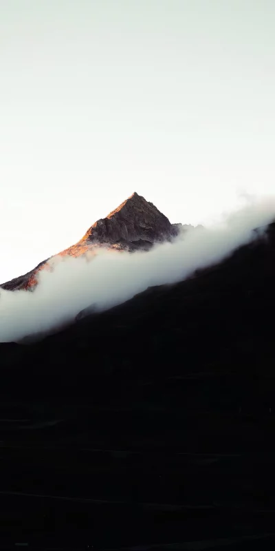 Dramatic mountain peak emerges from mist during sunrise