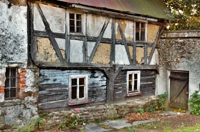 Weathered Half-Timbered House with Peeling Plaster and Rustic Wooden Siding image