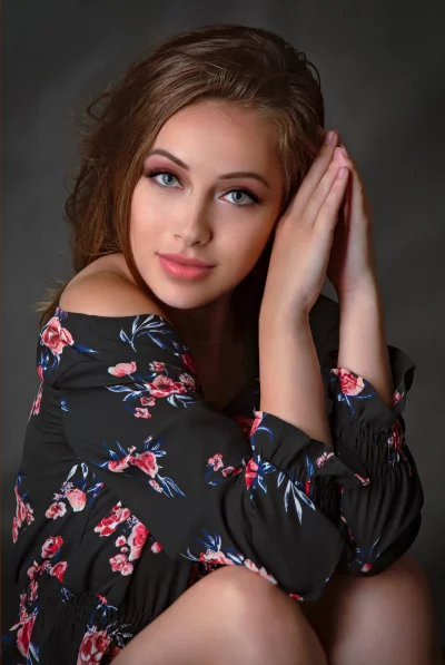 Pensive Young Woman in Floral Dress, Hands Clasped Elegantly image