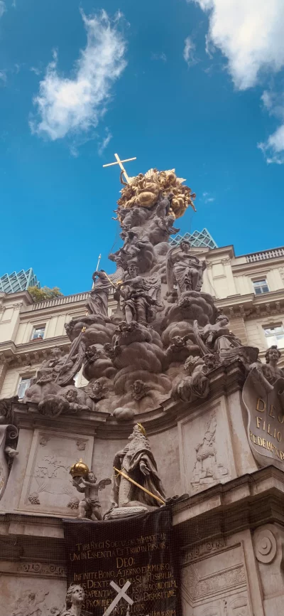 Ornate Baroque Column with Golden Cross Against Blue Sky