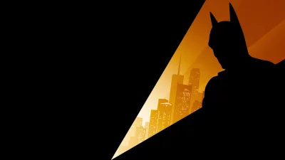Iconic Batman Silhouette Overlooking Glowing City Night with Spotlight image