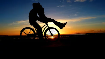 Romantic Couple Silhouette on Bicycle at Golden Sunset Beach image