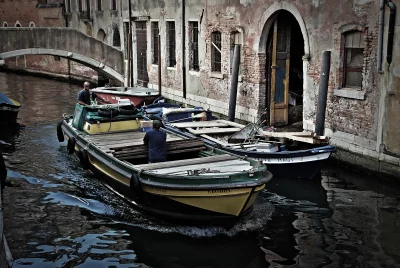 Traditional Boats Navigating a Grungy Venetian Canal Lined with Historic, Weathered Buildings image
