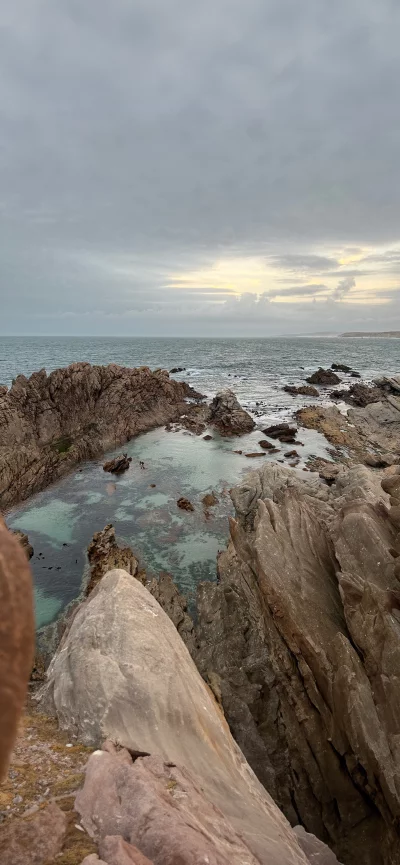 Rocky coastline with a natural tidal pool under a cloudy sky