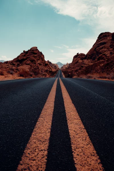 Desert Highway Winding Through Red Rock Formations to Distant Mountains image