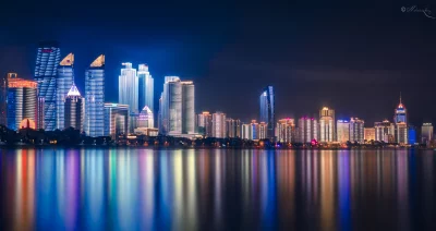 Vibrant Illuminated City Skyline Reflected on Tranquil Water at Night image