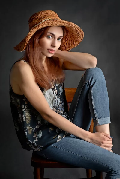 Red-Haired Woman Posing with Straw Hat and Floral Top in Studio image