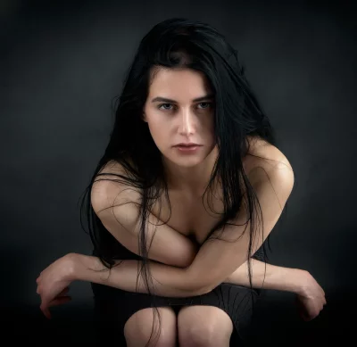 Pensive Young Woman with Intense Gaze, Long Dark Hair and Crossed Arms image