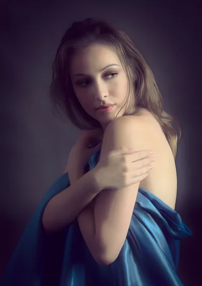 Pensive Young Woman Draped in Blue Satin Cloth with Elegant Expression image