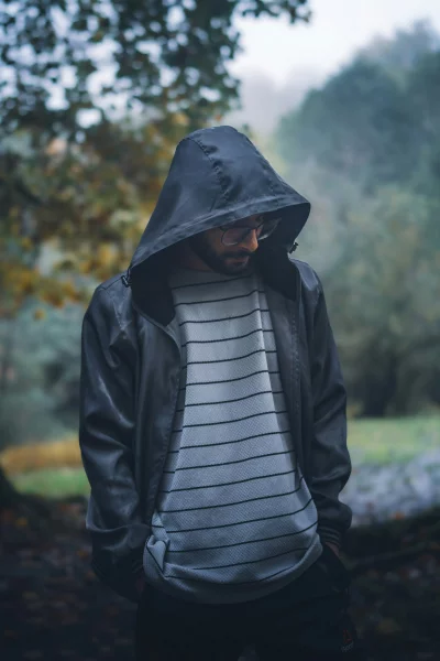 Man in Hooded Jacket and Glasses Standing in Foggy Forest