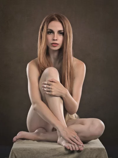 Nude Woman with Long Auburn Hair in Serene Seated Studio Portrait image