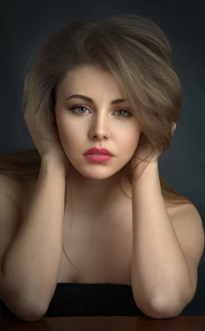 Young Woman with Expressive Gaze Posing with Hands on Head, Studio Portrait image
