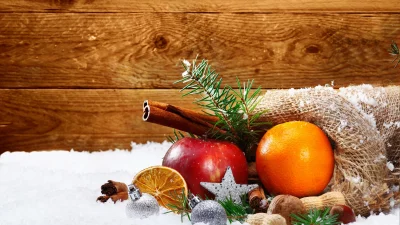 Vibrant Christmas Assortment with Apple, Orange, Nuts, and Ornaments on Snowy Wood image